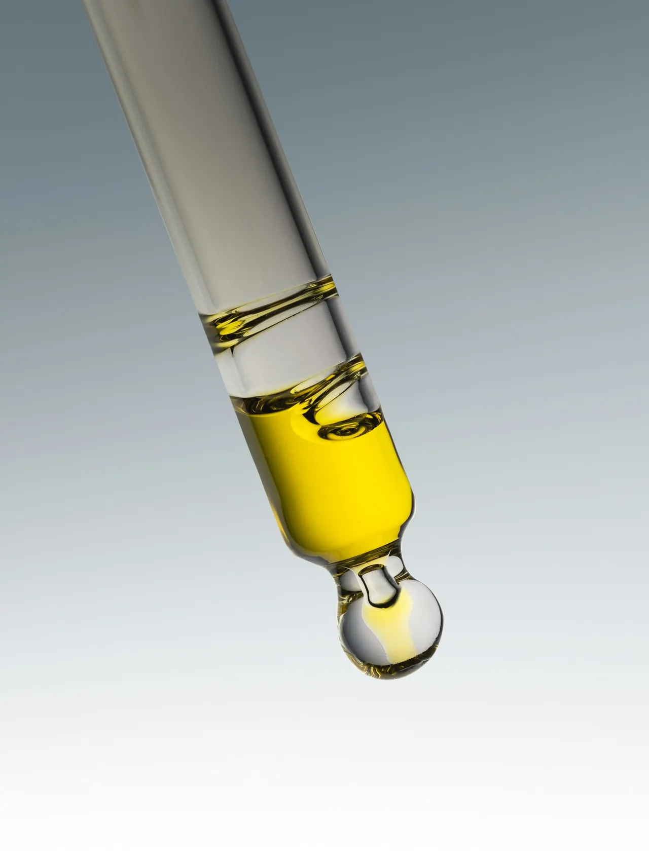 A pipette releasing a drop of yellow liquid
