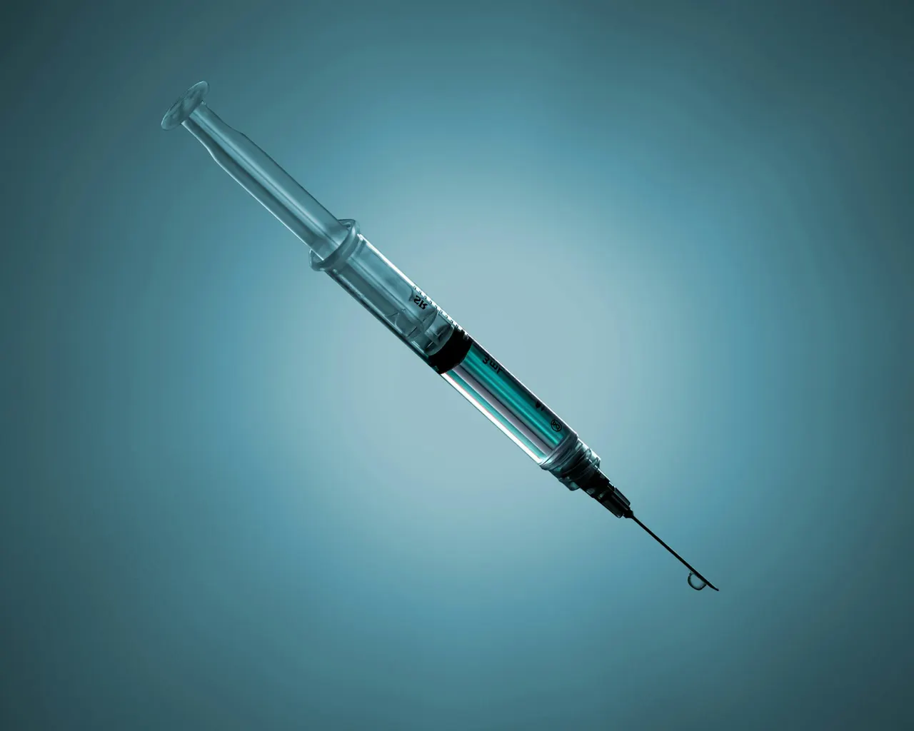 A syringe of clear liquid with a droplet at the needle tip