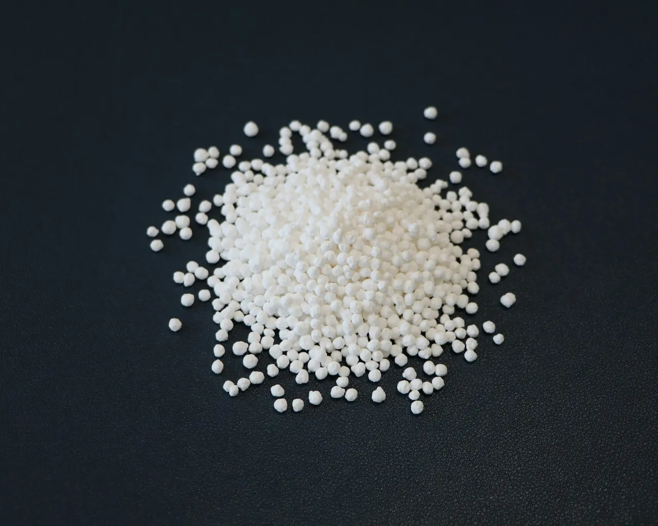 A pile of small white granules on a dark surface